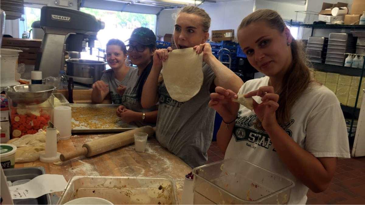 Un grupo de jóvenes trabajando y compartiendo felizmente en el oficio de la cocina en el campamento de verano del programa CC USA de Ventur Pipiol