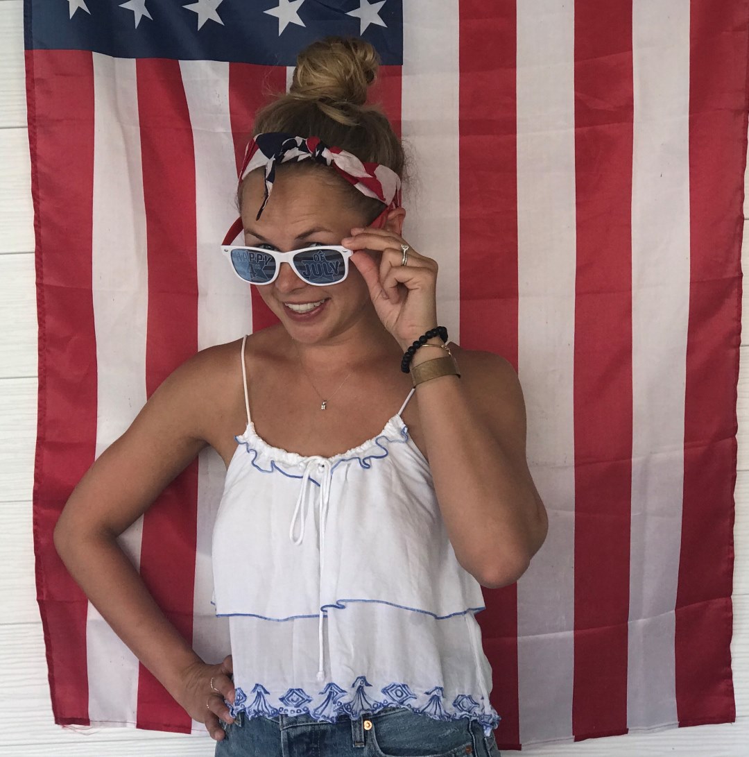 mujer rubia con gafas y bandera usa